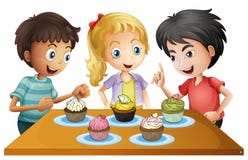 Trois enfants à la table avec des petits gâteaux Photo libre de droits